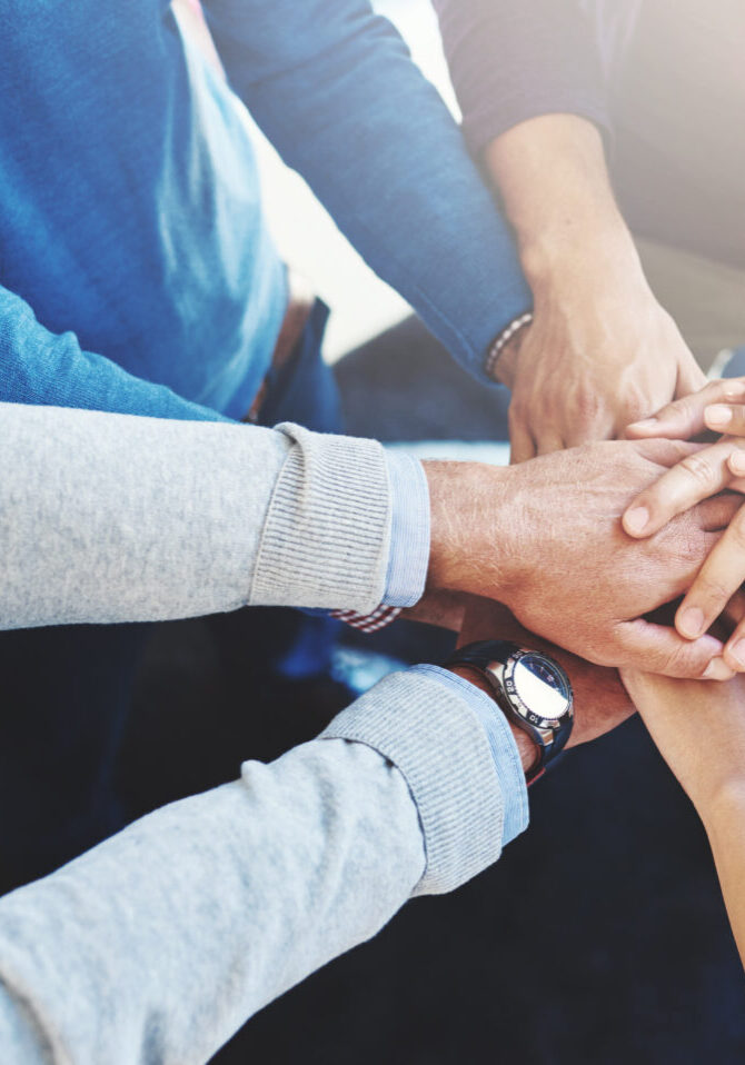 Cropped shot of a group of businesspeople standing in a huddle with their hands stacked.