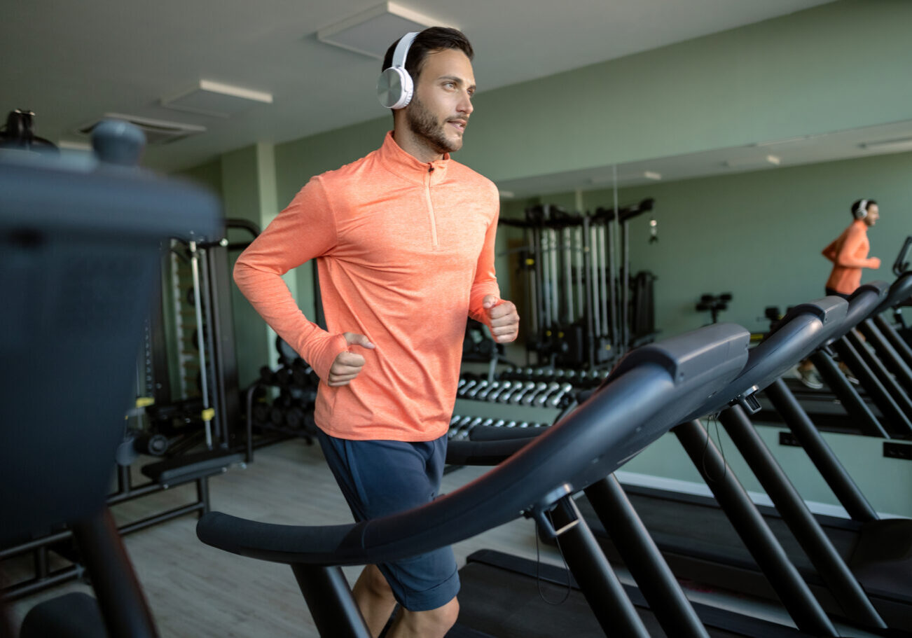 Young athletic man jogging on running track while exercising in health club.